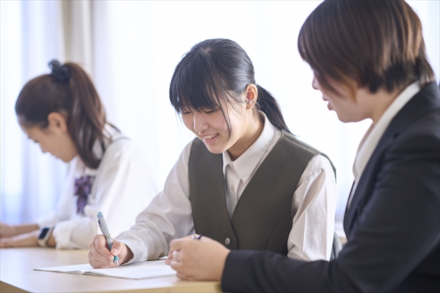 丁寧に説明する講師に教わる女子生徒の写真